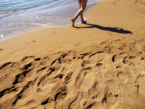close up young adult woman walking on sandy beach