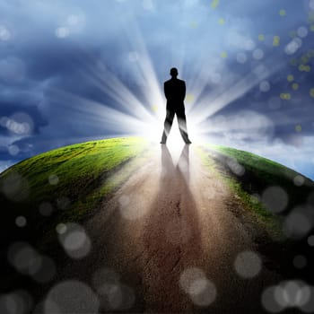 conceptual image of silhouetted businessman on empty road over cloudy sky with beam of light