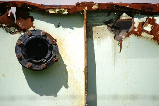 The side view of an old rusted metal container wall with a flange.