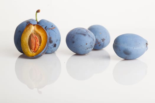 Untouched plum fruit with original color streight from tree, one plum divided in half