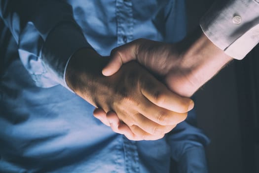 Handshaking of two business people. Partnership - Teamwork. Greeting, Form Of Communication. Light in scene come from down.