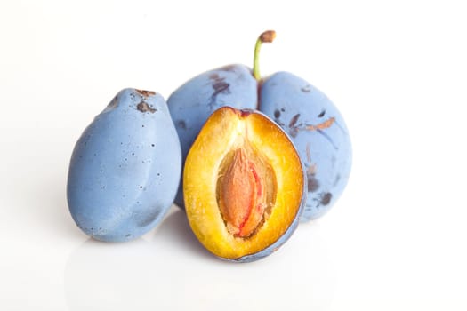 Untouched plum fruit with original color streight from tree, one plum divided in half