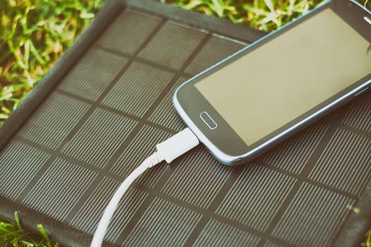 Use of renewable energy - Mobile Phone Chargers on grass in nature with Sun