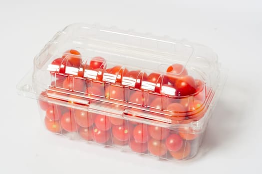 Cherry tomato in plastic cointainer packed and ready for market. Package of 500g, studio shoot on white