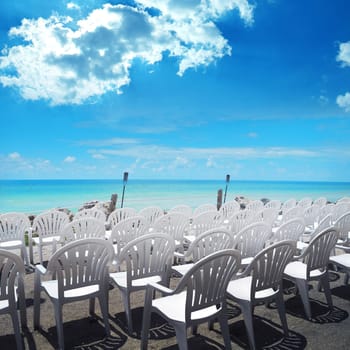 empty white chairs in a row at beach