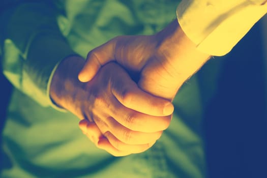 Handshaking of two business people. Partnership - Teamwork. Greeting, Form Of Communication. Light in scene come from down.