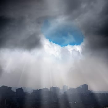 elevated view of city over cloudy sky and sun beams
