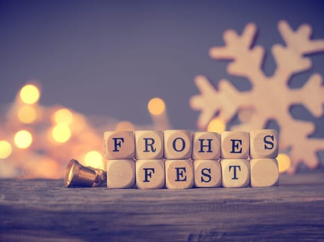 German Merry Christmas on wooden dices with blurred lights and decoration