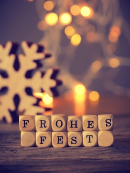 German Merry Christmas on wooden dices with blurred lights and decoration