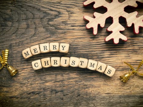 Merry Christmas on small wooden dices with Christmas decoration on a wooden board