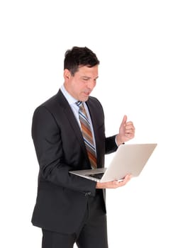 A tall business man standing in a dark suit and tie holding his laptop.in his hand is happy what his seen, isolated for white background.