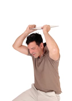 A very frustrated man sitting on a chair and likes to throw away his new.laptop, holding it over his head, isolated for white background.