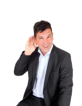 A handsome man has problem with hearing, holding his hand behind.his ear, sitting in a suit, isolated for white background.
