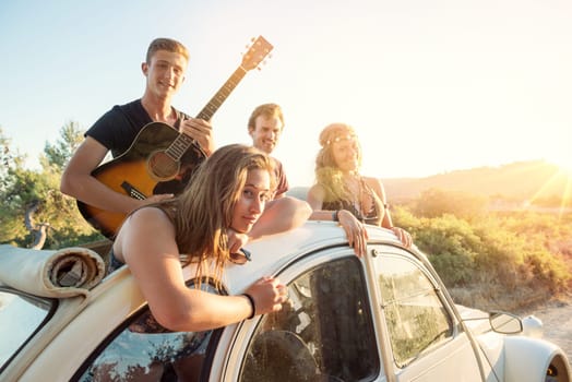 Group of happy people in a car at sunset in summer.