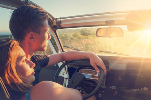 Happy couple in a car enjoying sunset.