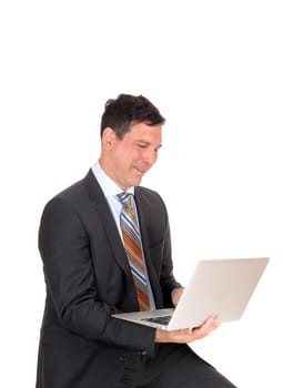 A handsome middle age business man sitting and working with his.laptop, smiling, isolated for white background.