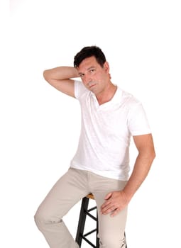 A handsome middle age man sitting on a chair with one hand behind his.head looking very serious, isolated for white background.