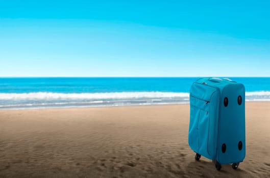 Blue suitcase on the beach. Summer travel concept