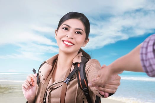 Smiling asian woman following her husband on vacation in the beach