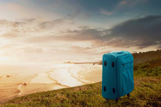 Blue suitcase on the cliff with seascapes view. Summer travel concept