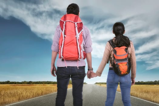 Romantic asian traveler couple holding hands and looking at view on savannah