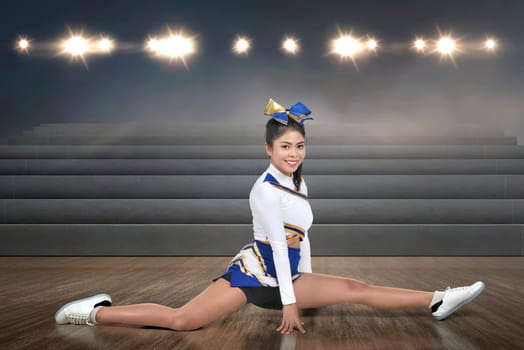 Smiling asian cheerleader doing splits at indoor arena