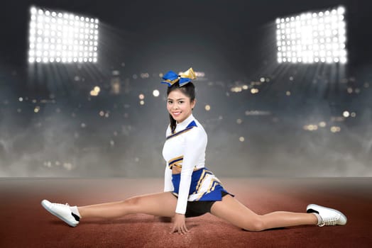 Beautiful asian cheerleader doing splits with spot lights background