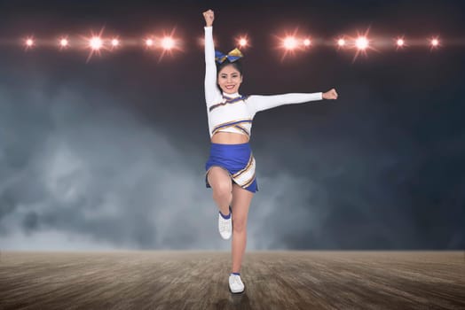Beautiful asian cheerleader in action with spotlights on background