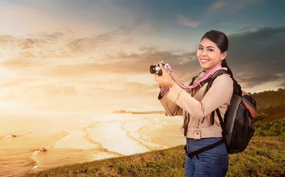 Happy asian photographer woman ready to take a photos with camera at sunset