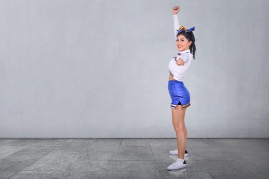 Smiling asian cheerleader in white and blue suit at indoor