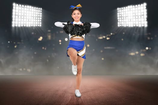 Young asian cheerleader in action with pom poms with spot light background
