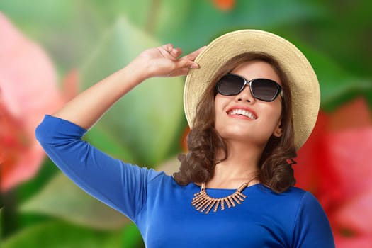 Smiling asian tourist woman with hat and eyeglasses over blurred background