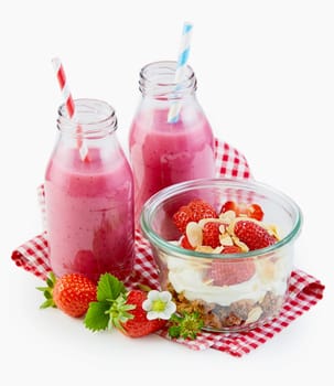 Healthy breakfast with strawberry smoothies and a bowl of crunchy muesli topped with yogurt and berries over white