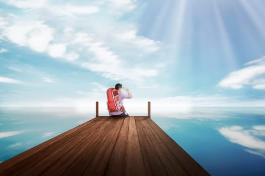 Attractive asian traveler man sitting and enjoying view from the dock
