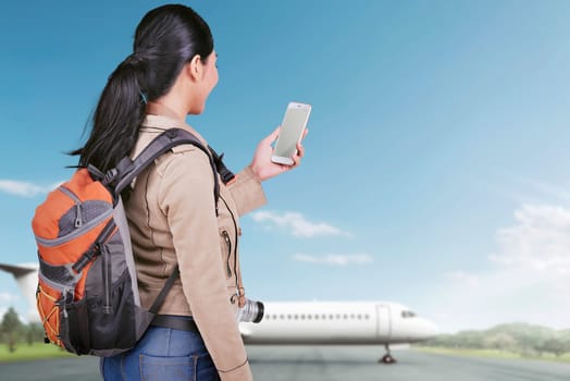 Happy asian tourist woman with phone going traveling with airplane on the background