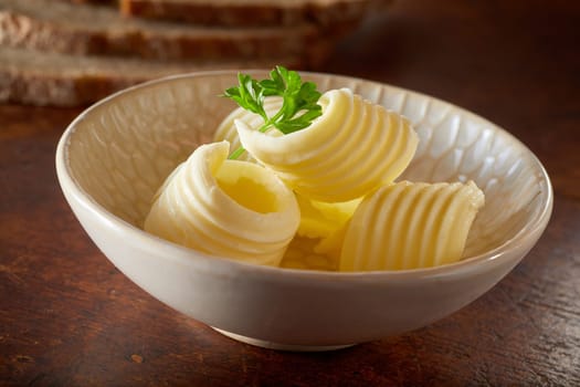 Close up Cute little bowl of fresh butter curls on wooden table for advertising, food ingredients for baking and cooking or for breakfast scenes.