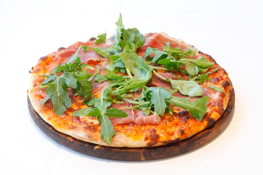 Pizza with rocket,Parma ham and cheese,on a wooden board,wise background