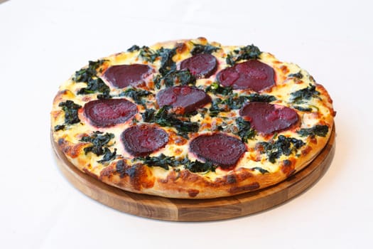 Pizza with beetroot,spinach and cheese,on a wooden board,wise background