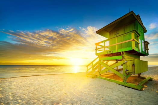 Miami South Beach sunrise with lifeguard tower and coastline with colorful cloud and blue sky.