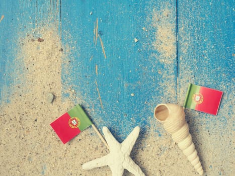 Vacation concept background with a small flag or Portugal and sand on beach wood
