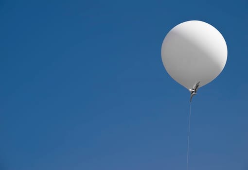A blank white balloon with space for text, over a clear blue summer sky