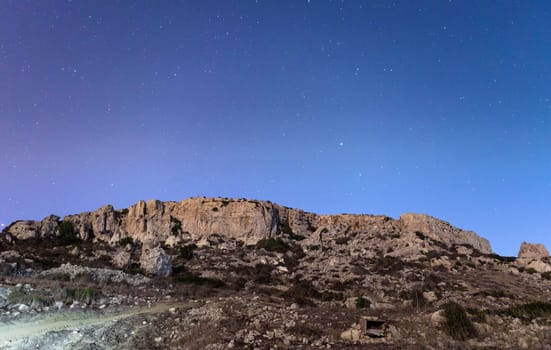 The cliffs at Mgiebah Bay in Malta, under a starry sky.