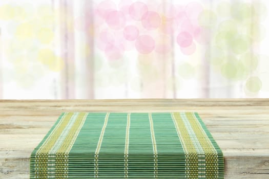 Empty table with green tablecloth over bright bokeh background. For your food and product display montage.