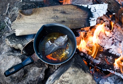 Brewing tea on a burning bonfire excellent to portray outdoor leisure activities such as camping