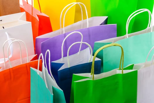 Variety of colored paper shopping bags on white background. Empty area.