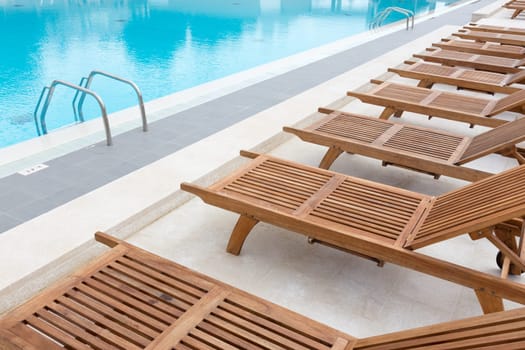 Luxury modern swimming pool with wooden sunbeds