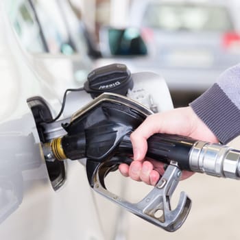 Pumping gas at gas pump. Closeup of man pumping gasoline fuel in car at gas station.