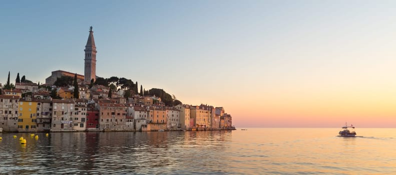 Colorful sunset of Rovinj town, Croatian fishing port on the west coast of the Istrian peninsula. Colorful evening seascape of Adriatic Sea. Traveling concept.
