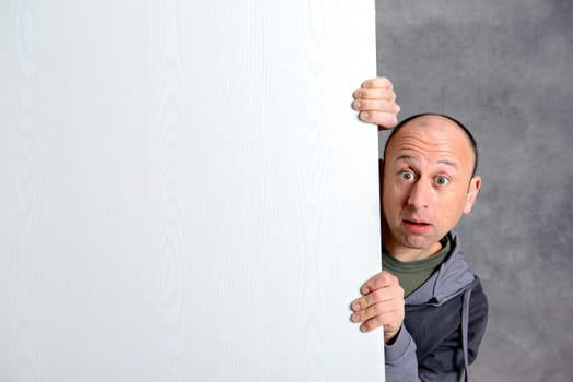 young man with a white advertising board in front of gray background