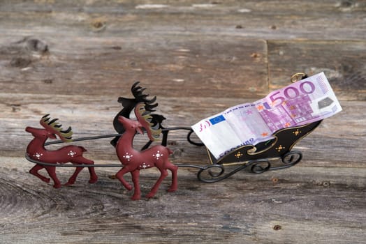 christmas sill with money in reindeer carriage , fir branch and candle